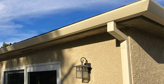 Aquasoltech seamless gutter system and downspout installed on a residential roofline in San Diego, shown against a clear blue sky to highlight professional rainwater management and home exterior protection.