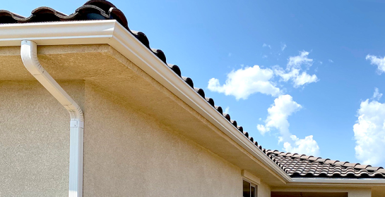 Aquasoltech seamless gutter system and downspout installed on a residential roofline in San Diego, shown against a clear blue sky to highlight professional rainwater management and home exterior protection.